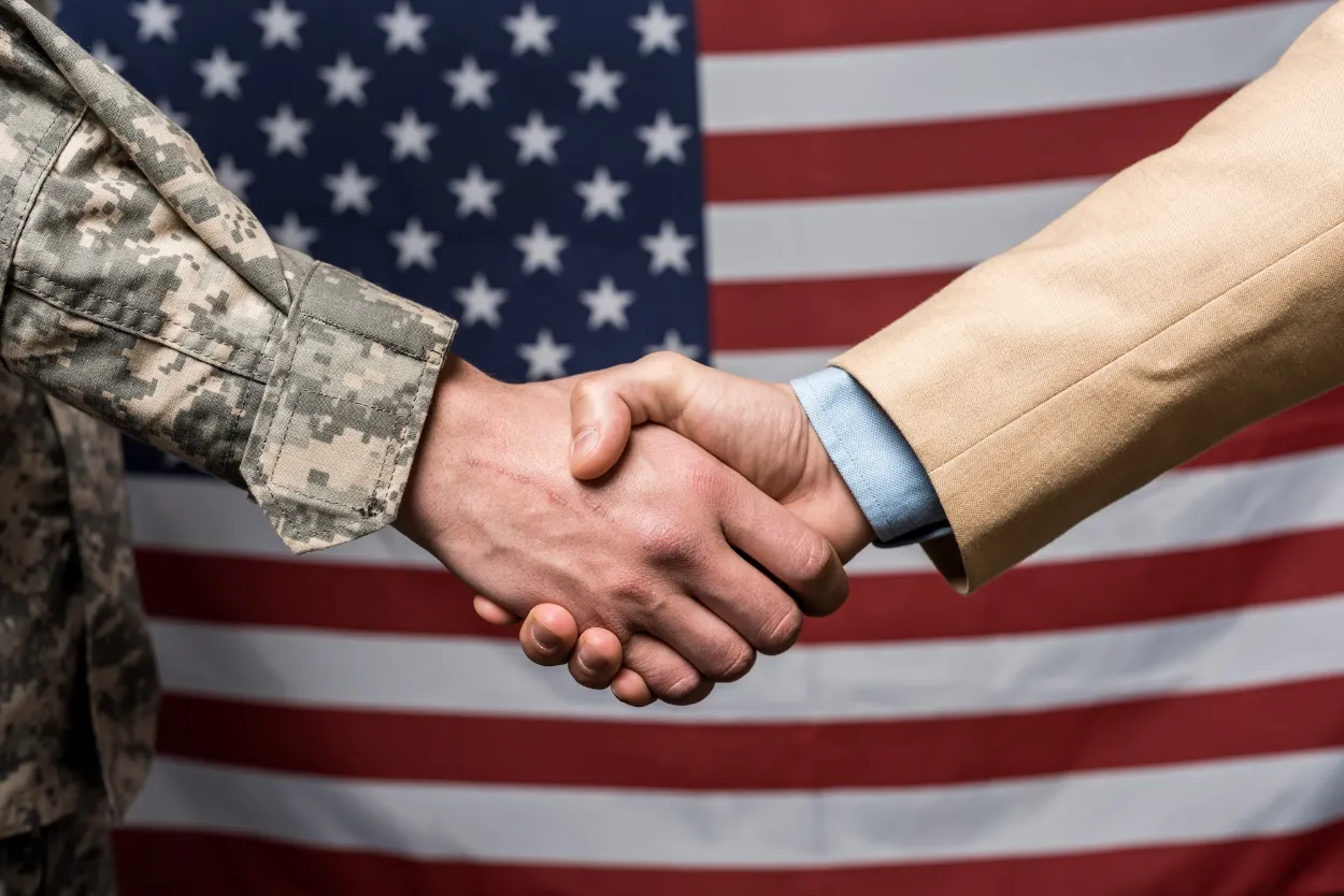 selective-focus-military-men-shaking-hands-near-american-flag